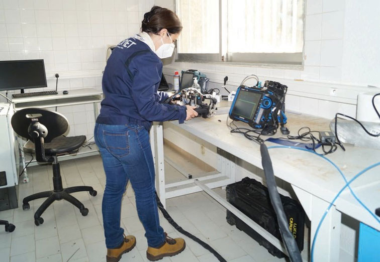 Onet Technologies nondestructive testing (NDT) expert using an AxSEAM scanner and OmniScan X3 phased array flaw detector in an in-laboratory setting to test the efficacy of the set up on circumferential and longitudinal weld seams in pipes.