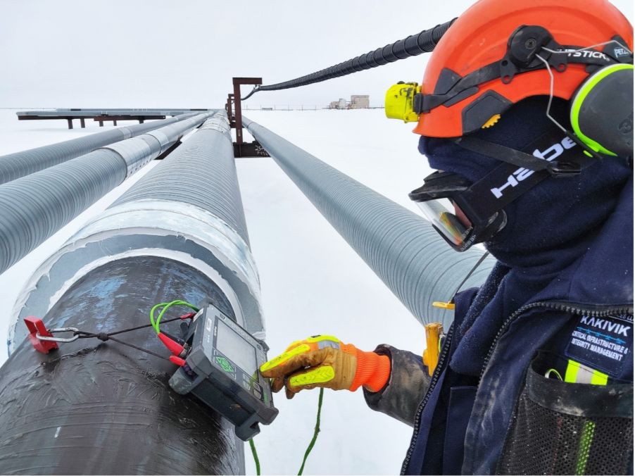 Operatore di Kakivik Asset Management mentre ispeziona una tubazione mediante la tecnologia di ispezione a ultrasuoni Evident in un'area petrolifera alascana coperto da neve