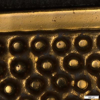 Uma imagem macro de um emblema automóvel. Os elementos redondos são saliências.